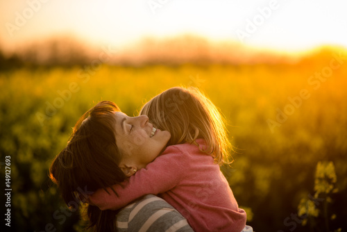 Little girl embracing her mom in the rapeseed field