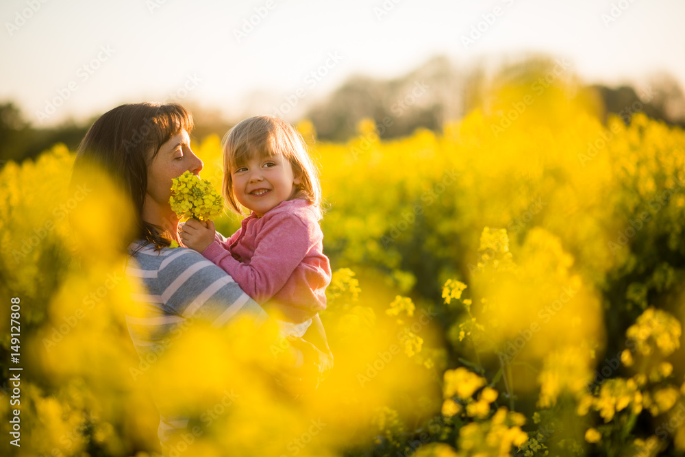Young woman with a baby in a field of rapeseed Young woman with a baby in a field of rapeseed