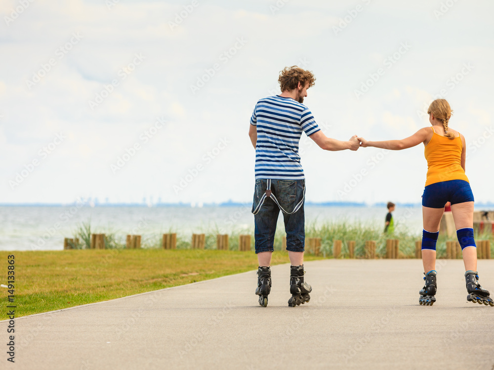 Fototapeta premium Young couple on roller skates riding outdoors