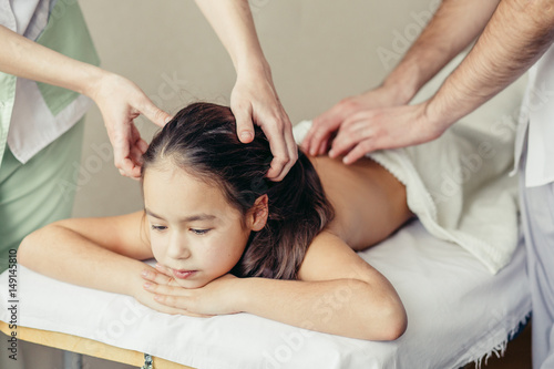 two Masseurs doing massage head a little kid
