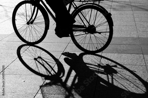 Black and white image of shadow of a cyclist. Motion blur.