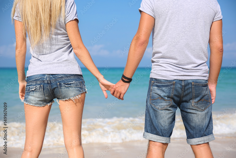 Happy couple walking hand in hand on white sand beach..Relaxing over natural background blue sky and sea. Love story Happy couple walking hand in hand on white sand beach..Relaxing over natural background blue sky and sea. Love story