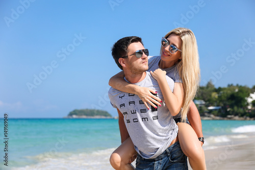 Young beautiful happy couple having fun on the beach. Piggyback rides. Positive human emotions, feelings. Love story © Ilya