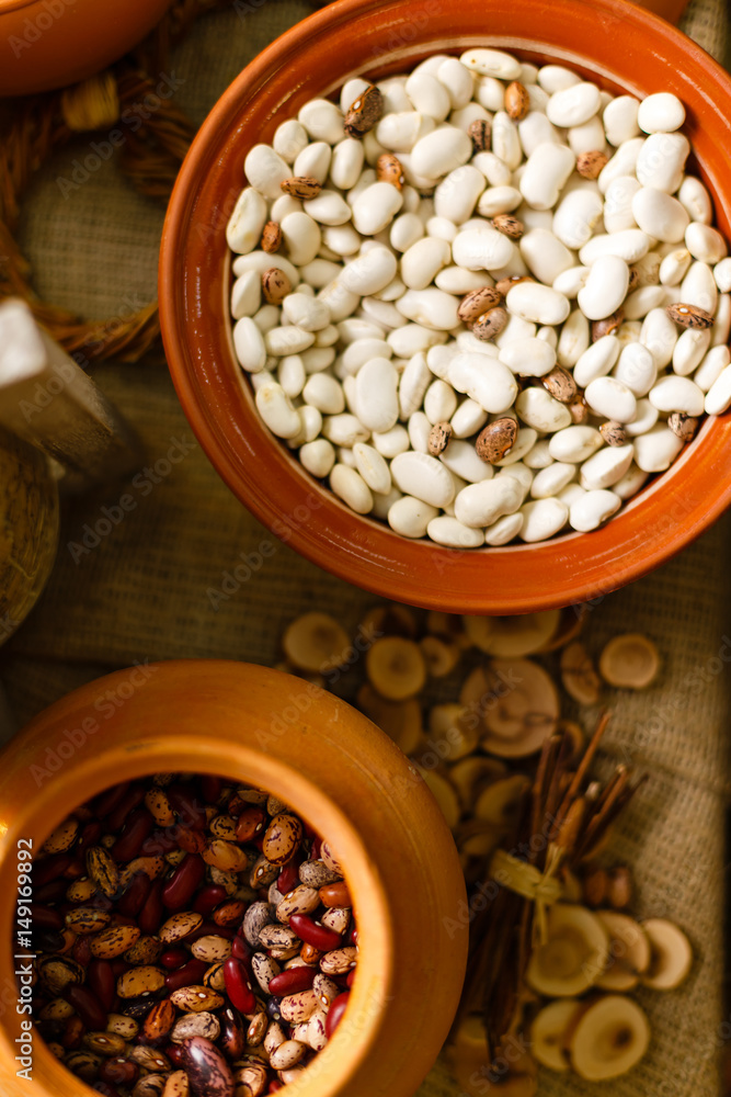 Colorful beans seeds in a clay ethnic painted plate on a dark background. Horizontal placement.