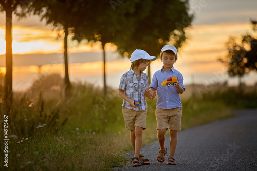 Two children, boy brothers, having fun outdoors with toy cars