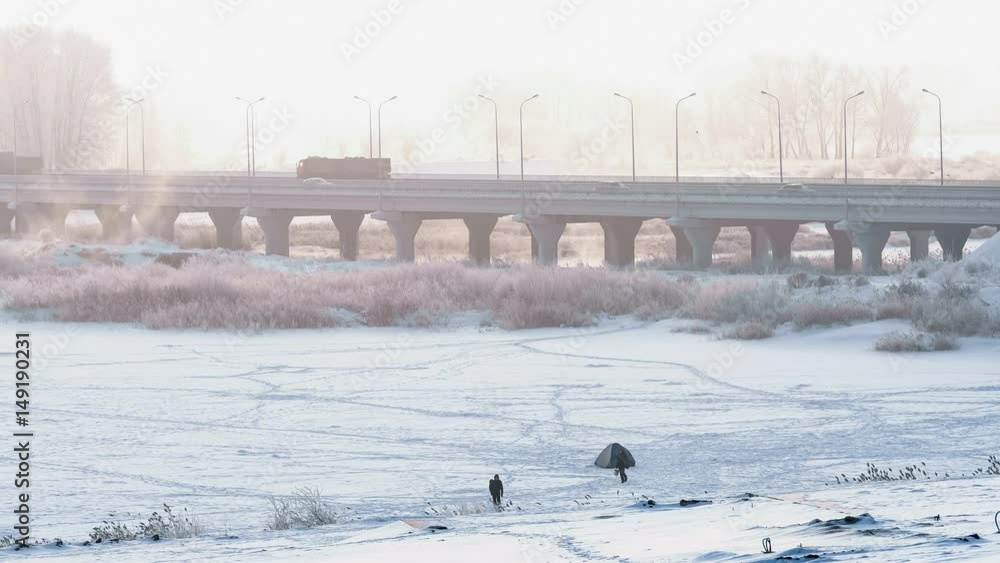 Wide shot of highway bridge acrossing frozen river in winter at frosty foggy dawn. Wide shot of highway bridge acrossing frozen river in winter at frosty foggy dawn.