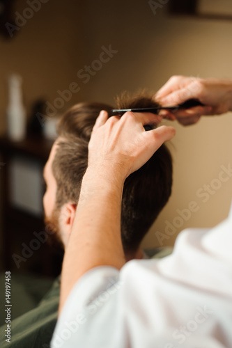 Master cuts hair and beard of men in the barbershop