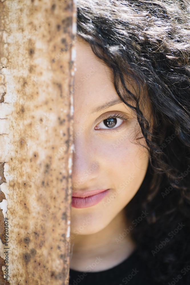 Pretty young girl peering from iron ancient door Pretty young girl peering from iron ancient door