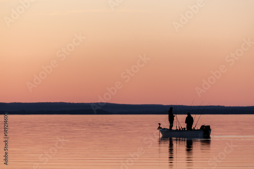 Two people fishing from small boat at sunset