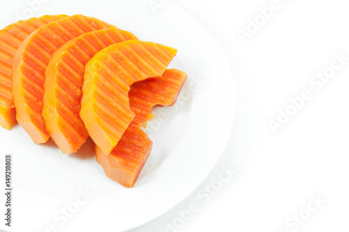Ripe papaya fruit sliced on a white dish on white background