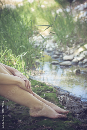 Woman resting in a calm, relaxing riverbank - Faceless portrait of a young girl barefoot in the riverside