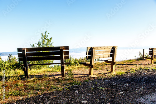 Wooden benches on top of a mountain overlooking the valley. Morning.