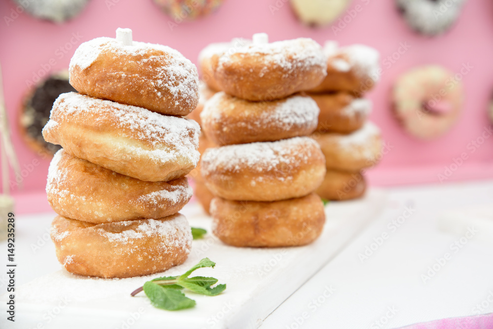 Picture of assorted donuts in a box with chocolate frosted, pink glazed and sprinkles donuts.