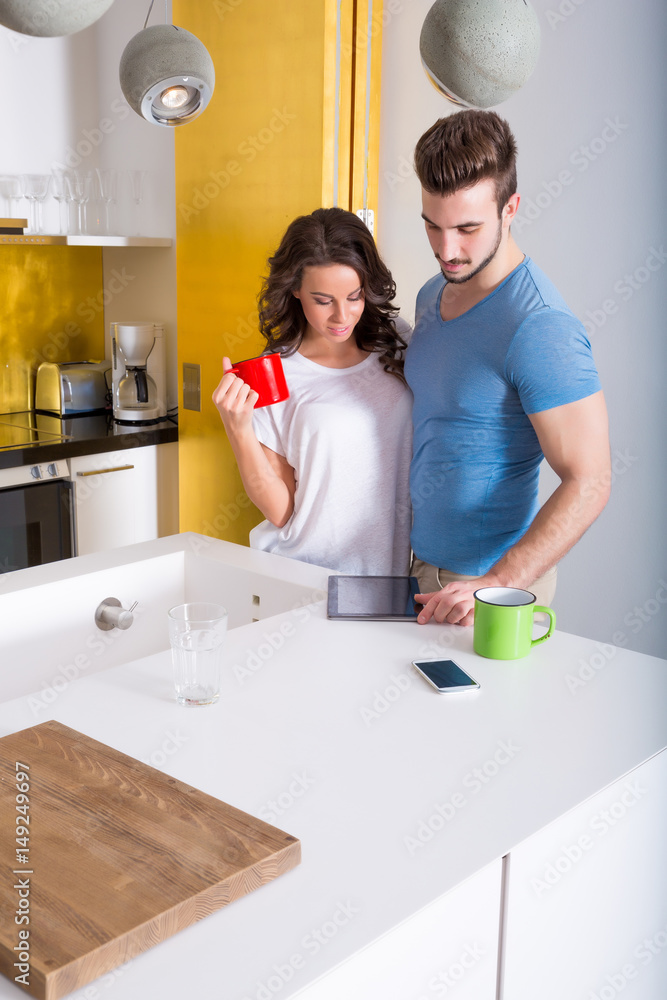 Young couple using a Tablet PC in the kitchen at home Young couple using a Tablet PC in the kitchen at home