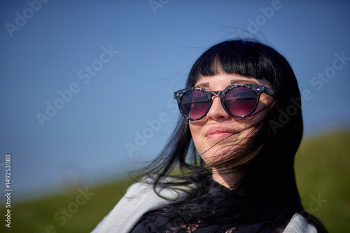 Beautiful brunette in sunglasses lies on the grass