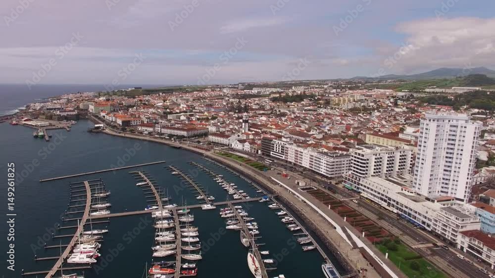 A view on Ponta Delgada from marina, Sao Miguel, Azores, Portugal. Moored yachts and boats along the port piers on a beautiful morning. A view on Ponta Delgada from marina, Sao Miguel, Azores, Portugal. Moored yachts and boats along the port piers on a beautiful morning.