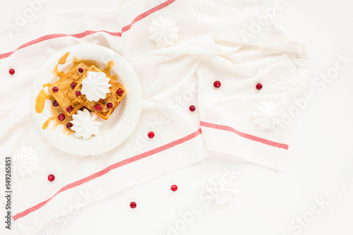 Plate of belgian waffles with caramel, meringue and berry on white background. Flat lay, top view