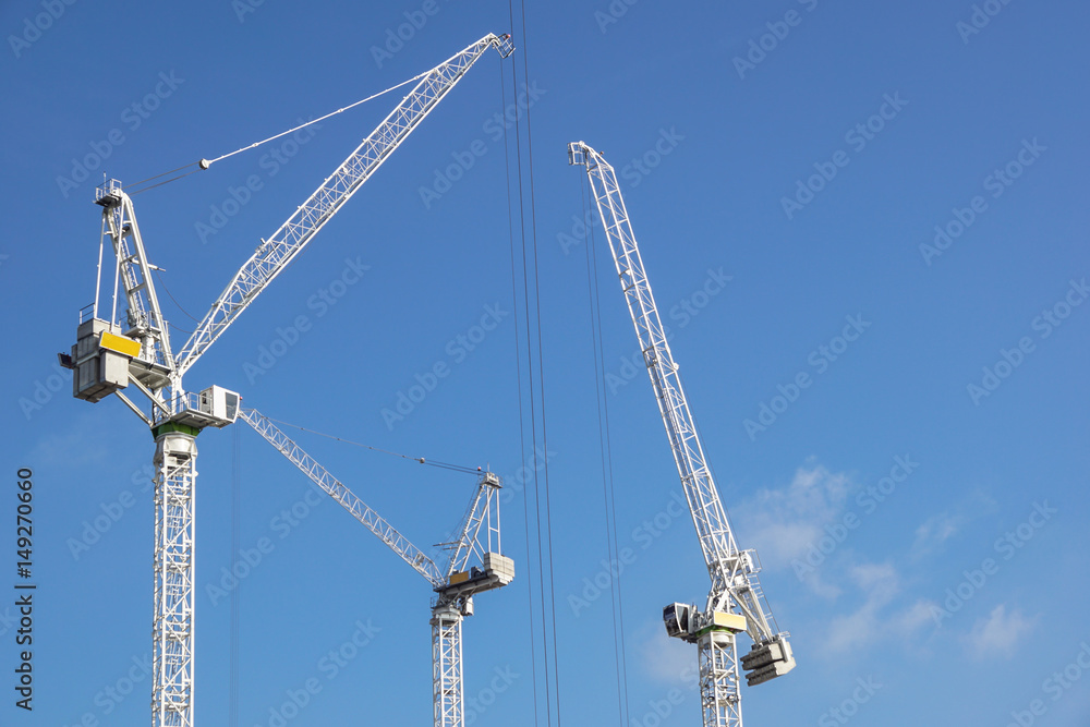 Tall white tower crane against bright blue sky. Tall white tower crane against bright blue sky.
