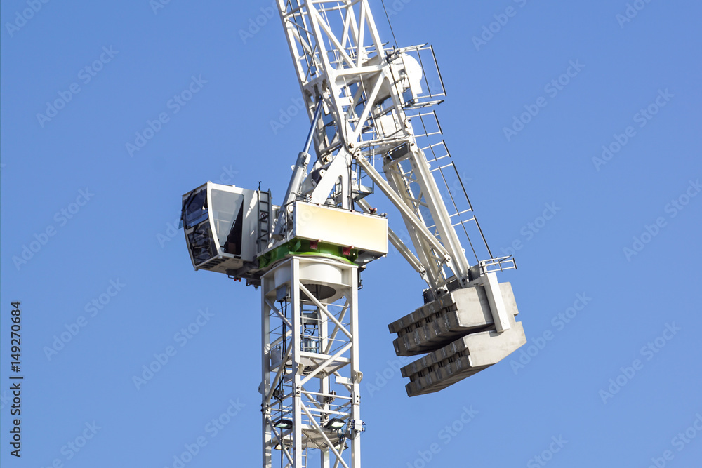 Fototapeta premium Tall white tower crane detail against bright blue sky.