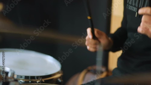 Studio man from band in black modern sweatshot playing on the drums and drum-type plates photo