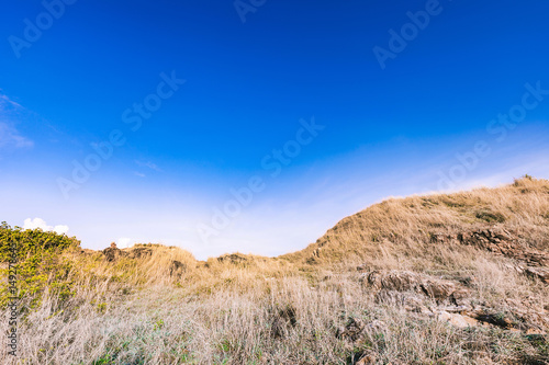 Beautiful rocks mountain lanscape and dry meadow in bright blue sky