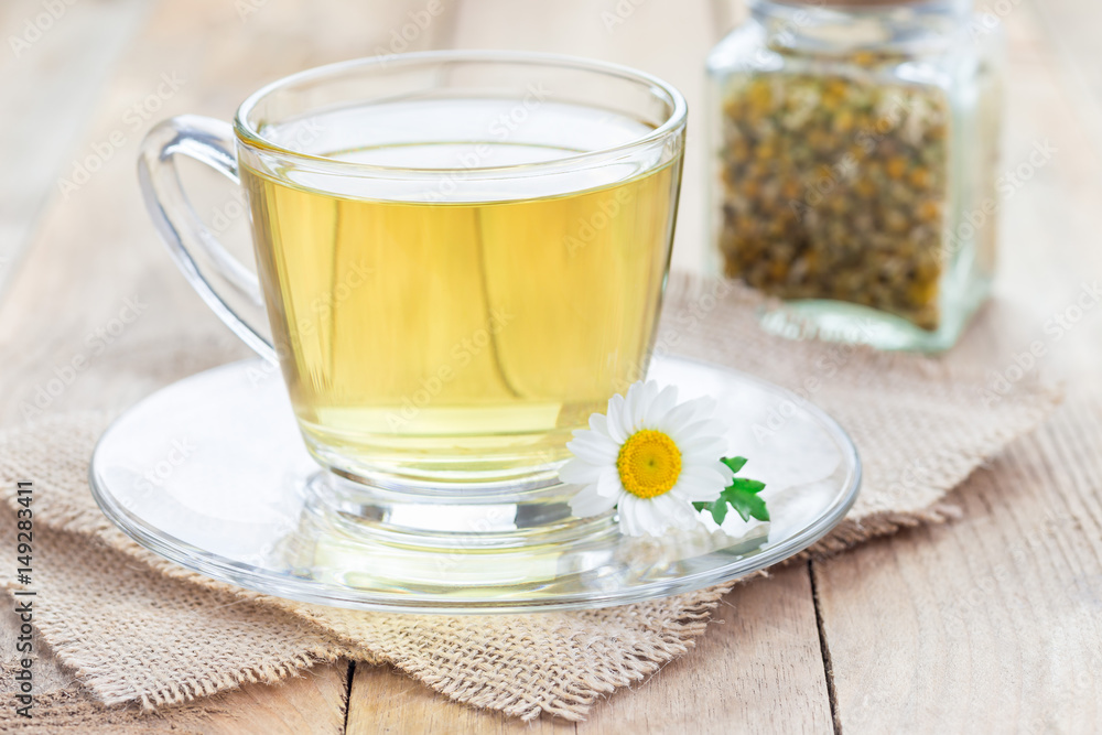 Chamomile tea in glass cup, chamomile flowers and dry tea on background, horizontal Chamomile tea in glass cup, chamomile flowers and dry tea on background, horizontal