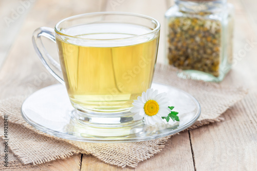 Chamomile tea in glass cup, chamomile flowers and dry tea on background, horizontal