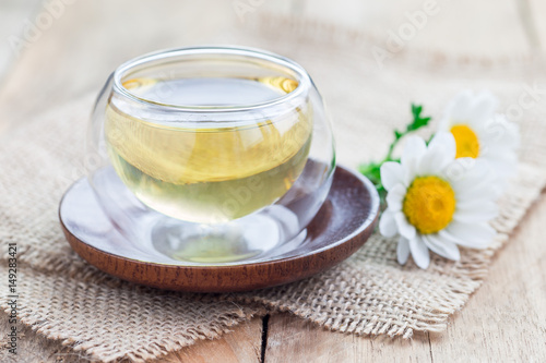 Chamomile tea in glass cup, chamomile flowers on background, horizontal