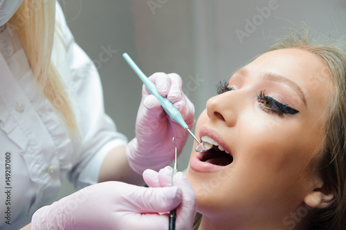 Doctor in uniform checking up female patient's teeth in dental clinic