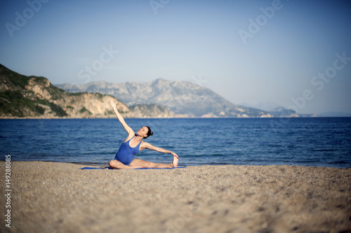 Beautiful young woman in her ninth month of pregnancy doing yoga on the beach
