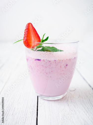 Blueberry smoothie with strawberry on white wood background. Fresh milkshake