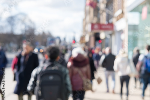 Blurred image of People walking on the street, with car, building in background. On Princes Street, the main shopping street in Edinburgh, United Kingdom.