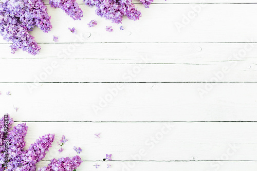 Floral pattern of lilac branches and petals on white wooden background. Flat lay  top view. Floral purple frame