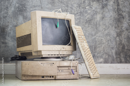 old and obsolete computer set on the floor with grunge concrete wall background, vintage color tone
