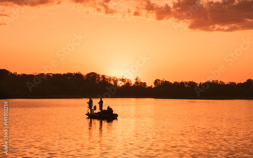 People are boating and fishing under sunset © Yan