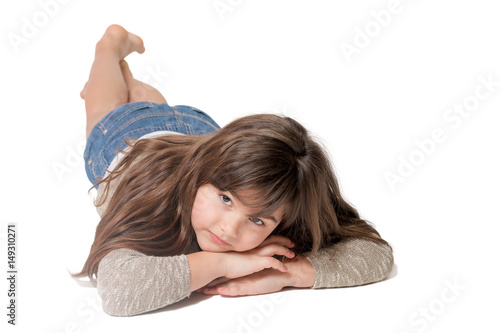 Cool brunette long haired little girl is lying on the light gray background. 