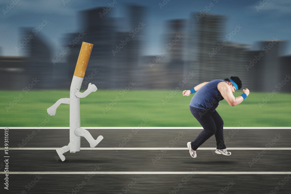 Fototapeta premium Obese man running away from a cigarette