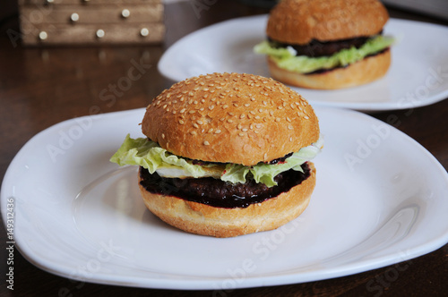 Two burgers with berry sauce on white plates