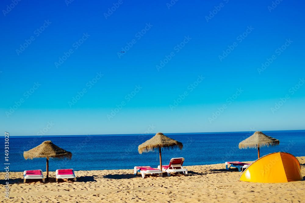 Beach umbrellas and couches on outdoors blue sky background