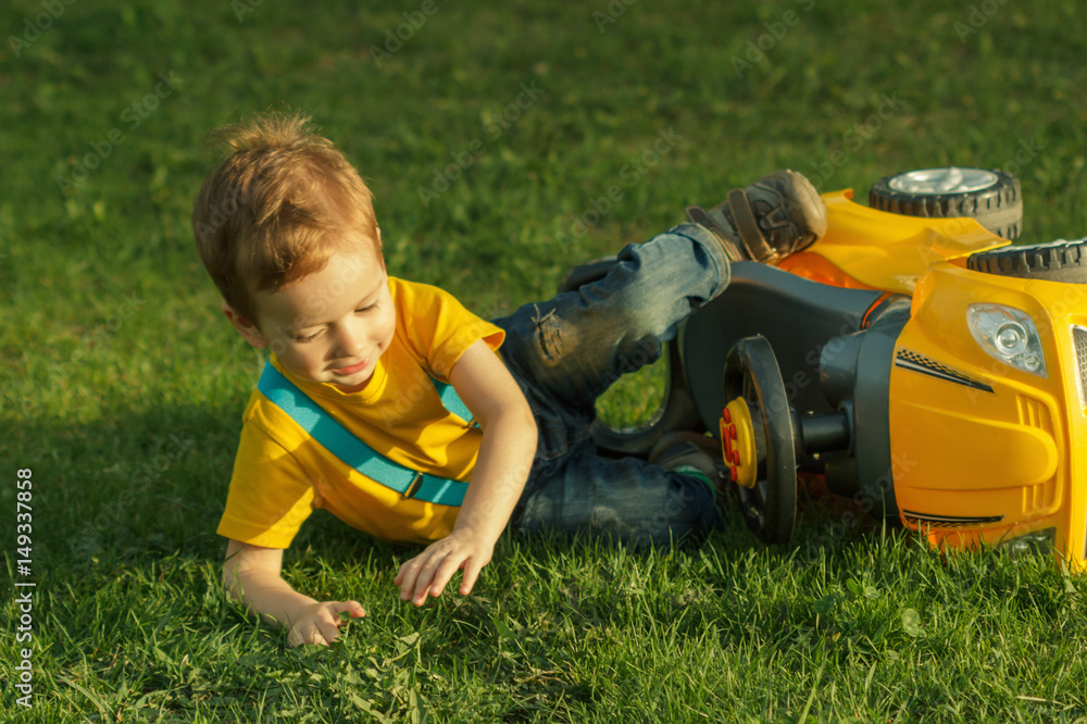 Cute positive kid, playing happily with baby car on green meadow Cute positive kid, playing happily with baby car on green meadow