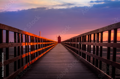 Fototapeta Naklejka Na Ścianę i Meble -  Sunset in Lignano Sabbiadoro, with a lighthouse at the end of a pier