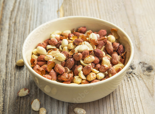 Peanuts in a bowl on wooden background, healthy fats snack
