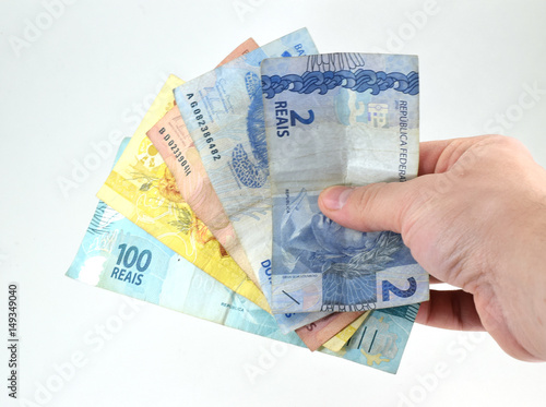 Hand holding Brazilian currency bills (real and reais) isolated, white background