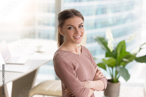 Schilderij op canvas Head shot portrait of happy smiling young businesswoman standing with arms cross