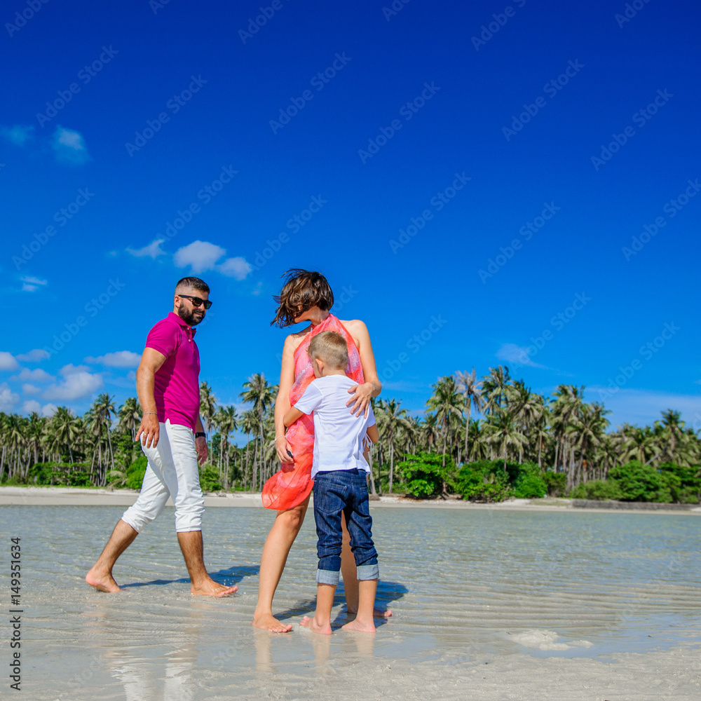 The happiest childhood: father, mother and son having fun on the tropical beach