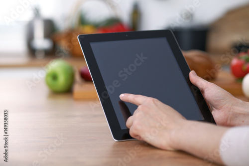 Haman hands  using touch pad in the kitchen. Closeup of woman making online shopping by tablet computer and credit card.  Cooking and shopping concept