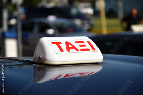Taxi sign in Greek language on the shiny roof of a car