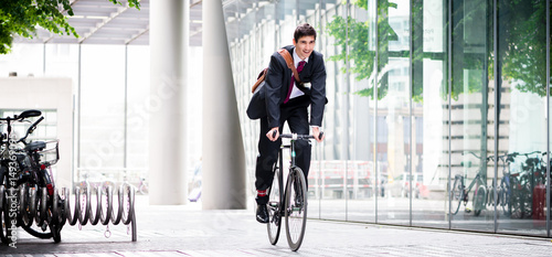 Photography Cheerful young employee riding an utility bicycle in Berlin