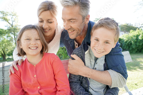 Portrait of happy family of four sitting on bench © goodluz