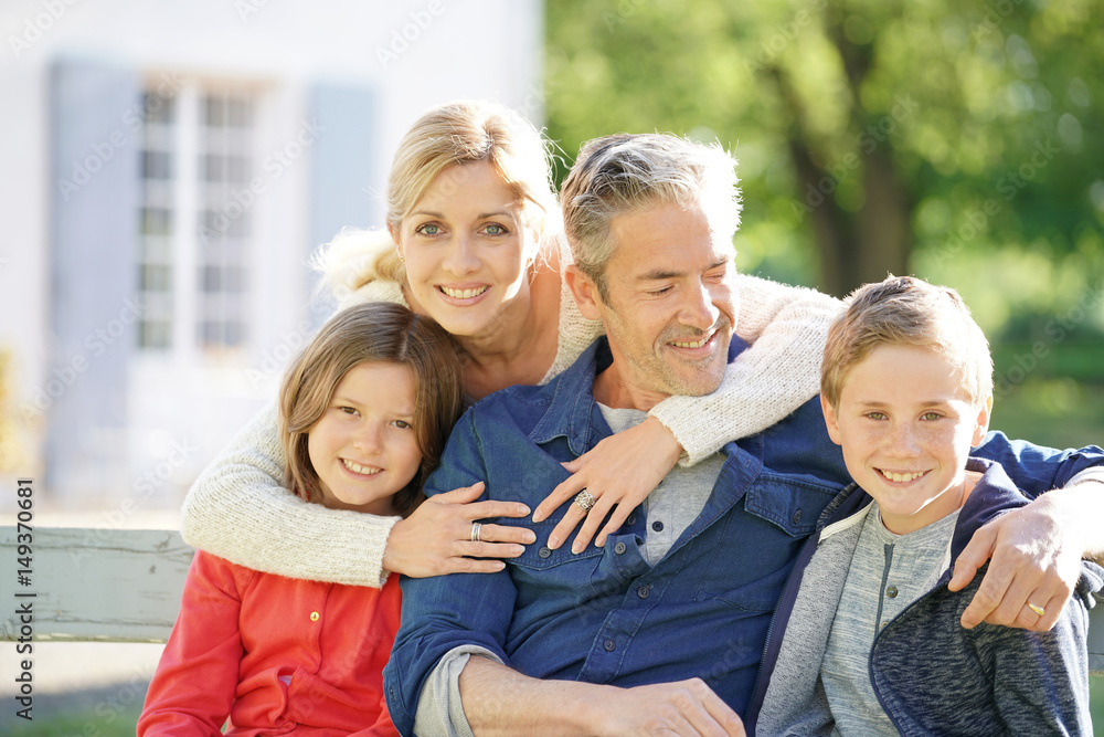 Portrait of happy family of four sitting on bench Portrait of happy family of four sitting on bench